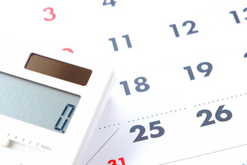 Fototapeta premium カレンダーを眺めながら電卓を叩いて、給料日の25日を待ち望んでいるイメージ 