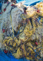 Industrial fishing nets on waterfront. A pile of fishing nets lying on blue background are necessary tools for catching fish