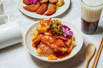 Sweet and sour fish fillet, Assorted Fried Snacks, fish cake, Taiwanese red bean ice tea served in dish isolated on marble background side view of taiwan food