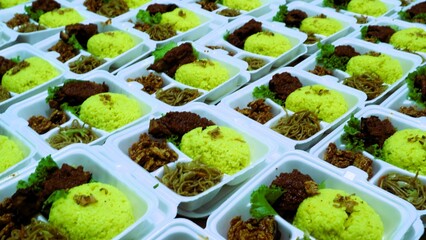 Large amount packages of yellow rice, noodles, and grilled chicken served in foam food container