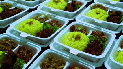 Large amount packages of yellow rice, noodles, and grilled chicken served in foam food container