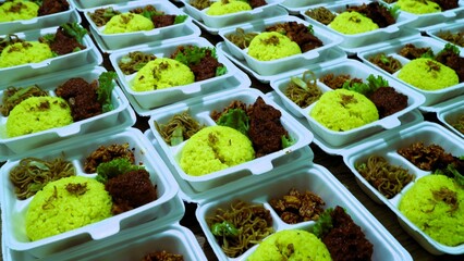 Large amount packages of yellow rice, noodles, and grilled chicken served in foam food container