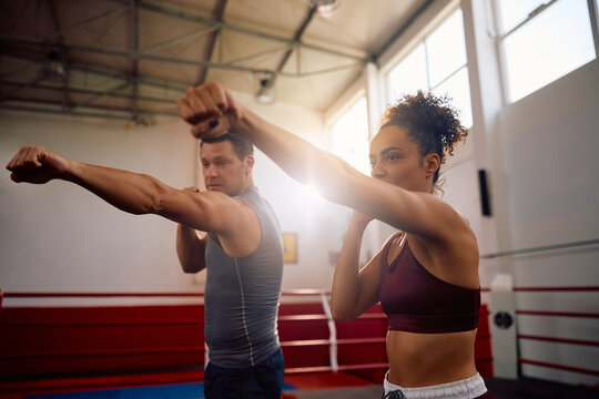 Young fighter practicing with her coach at health club.