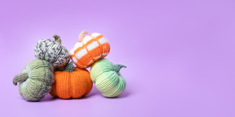 Knitted orange and striped pumpkins on purple background. Knitted autumn story with your own hands. Concept of autumn, Thanksgiving, harvest, Halloween