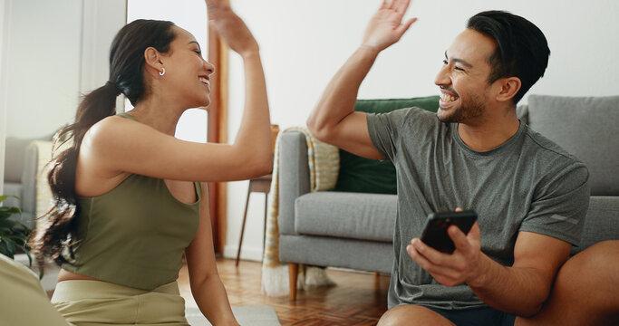 Happy couple, fitness and high five with phone for success, teamwork or workout goals together at home. Excited man or woman touching hands for winning, achievement or completion of exercise at house