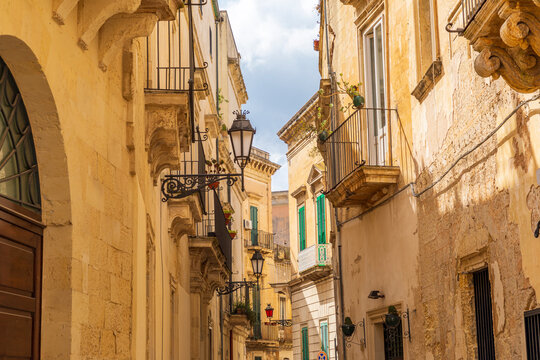 Italy, Apulia, Province of Lecce, Lecce. Stone buildings and iron balconies along a narrow street.