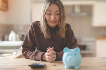 Woman Budgeting With Calculator and Piggy Bank in Cozy Kitchen Setting