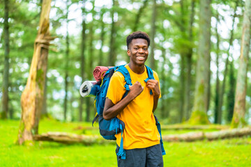 Naklejka premium A Young african man hiking through green forest