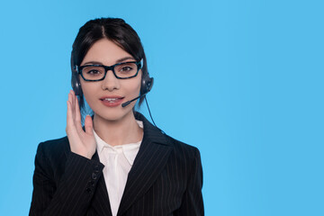 Young Woman in Suit Using Headset and Smiling Against Blue Backdrop