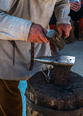 A blacksmith forges a piece on an anvil