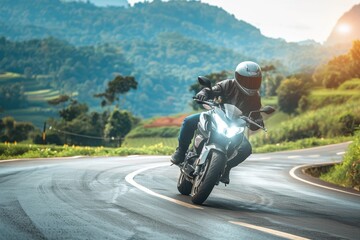 Young man on motorcycle on curving asphalt road with rural and mountain scenery