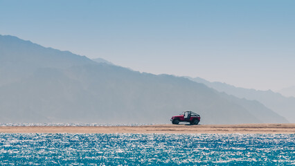 offroad car on an island in the Red Sea against the backdrop of high cliffs in Egypt