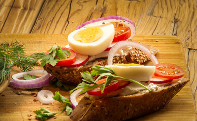 Sandwiches with tomatoes, onions and eggs lie on a wooden plate. Sandwiches on a wooden cutting board. Proper nutrition.