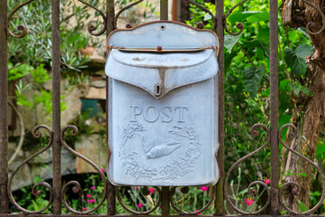 Beautiful old light blue and weathered metal mailbox or letterbox with the word post and an image of a swallow on an old fence in Cornac Lot Occitanie in Southern France