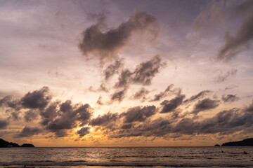 Sunset over the water with clouds against the sunlight on the Andaman Sea, Patong, Phuket, Thailand.