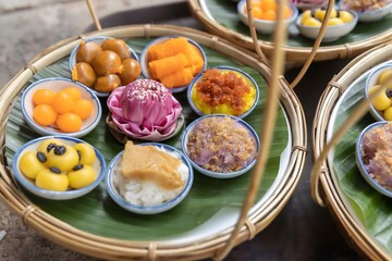 A highangle shot of a traditional Thai dessert table with an assortment of sweets like luk chup, thong yip, and khanom chan, set on a rustic table