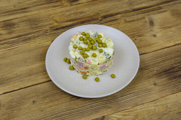 Ceramic plate with new year salad olivier on a wooden table