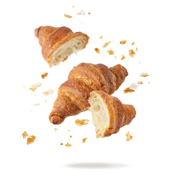 Fresh baked butter breakfast croissants and crumbs falling flying isolated on white background. Whole and broken in half croissants.