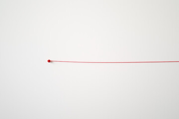 A red string is stretched out on a white wall