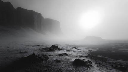 Fototapeta premium A mysterious foggy landscape with rocky cliffs and a glowing sun, casting an ethereal light over the scene.