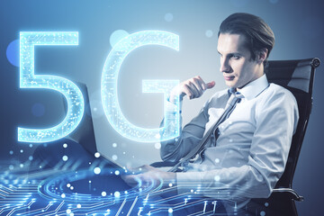 Attractive young european businessman sitting and using laptop with glowing 5G circuit hologram on blurry bokeh circles background. Mobile internet speed concept. Double exposure.