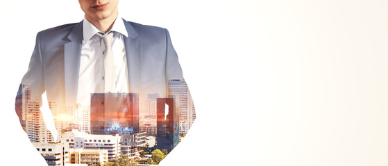 Headless young man with folded arms standing on abstract white city background with wide white mock...