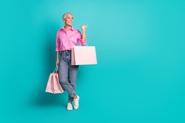 Fototapeta premium Full body portrait of nice aged lady bags indicate finger empty space wear shirt isolated on turquoise color background