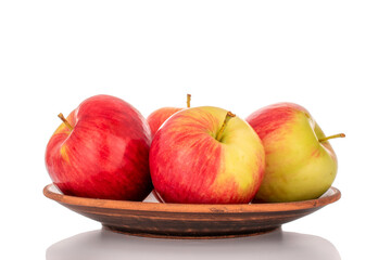 Several red apples on a clay plate with a knife, macro, isolated on a white background.