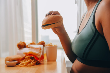 Binge eating disorder concept with woman eating fast food burger, fired chicken , donuts and...