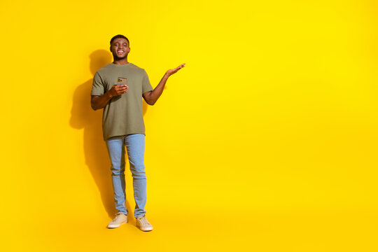 Photo of cheerful attractive nice man wear khaki stylish outfit recommed empty space store isolated on yellow color background