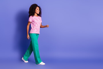 Full body photo of attractive young woman walking empty space dressed stylish pink clothes isolated on violet color background