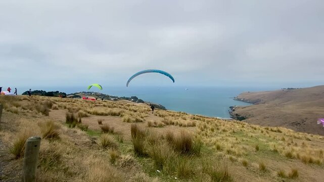 People parachuting at Godley Head Walkways , Awaroa ,Christchurch New Zealand, paraglider over the mountains