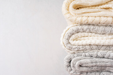 Close up view of stack of folded soft warm comfortable casual woven sweaters or cardigans knitted...