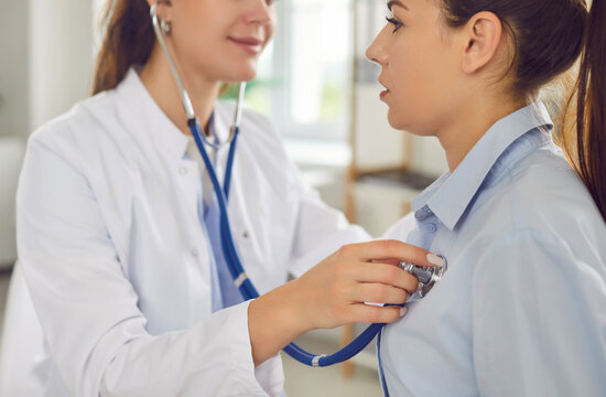 Female doctor uses stethoscope to examine young girl patient to check heart rate, lungs in clinic, smiling caring woman nurse, phonendoscope listening to heartbeat in hospital, checkup medical visit 