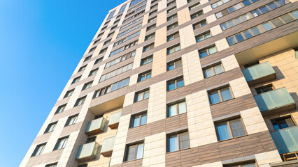 Moscow, March 19 2024, A large building with many windows and a balcony. The building is brown and white. The sky is blue