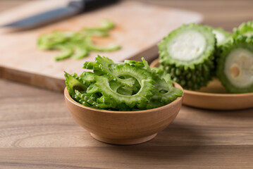 Sliced bitter gourd in bowl on wooden background, Food ingredient