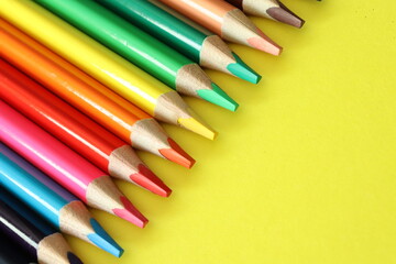 a group of multi-colored colorful large pencils on a yellow background