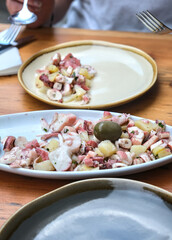 Octopus salad in an oval plate, on a restaurant table.