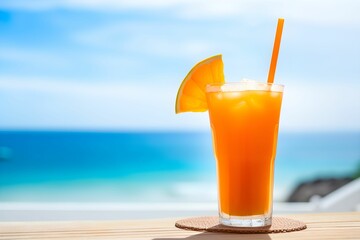 Glass of orange juice on wooden table on the beach, blue seashore background