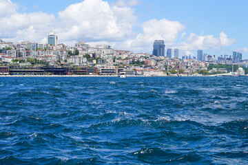 A captivating view of the modern Istanbul skyline as seen from the Bosphorus Strait. The vibrant blue waters contrast with the urban landscape filled with diverse architecture