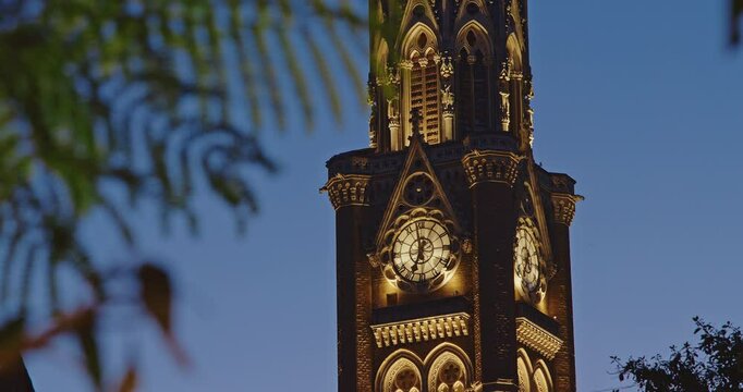 Close-up view on Rajabai Clock Tower In Evening Illumination. Clock Tower In Mumbai India. Confines Of Fort Campus Of University Of Mumbai. It Stands At Height Of 85 M or 280 Ft. Modeled It On Big Ben