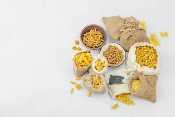 Pasta. Various kinds of uncooked pasta and noodles over light stone background. Traditional Italian
