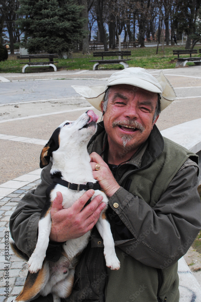 Wall mural man smiling and holding jack russel terrier in hands in the park