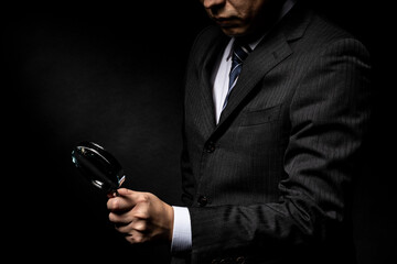 拡大鏡を手に持ったスーツ姿の男性