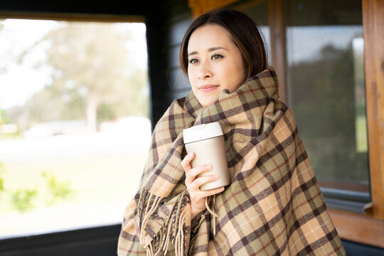 ストールにくるまってコーヒーカップを持っている女性