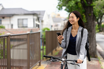 笑顔で自転車通勤する女性・スマートフォンの操作