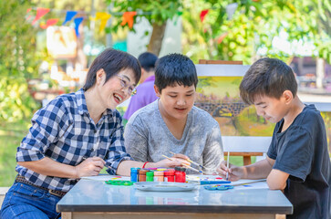 middle aged asian woman teacher enjoy teaching the young teens student at school art club outdoors, concept of adult help teenage pupils doing school art project