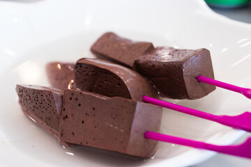 The coagulated pig's blood is cut into pieces and skewered with a stick.