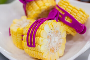 Fresh sweet corn cut into sections and clamped with a purple stick.