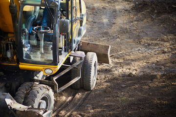 An empty bulldozer cabin stands idle on a construction site, surrounded by compacted soil. Pause in construction work, workers' strike, beginning of construction work.